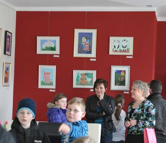 Kinder vor ihren ausgestellten Bildern bei einer öffentlichen Ausstellung