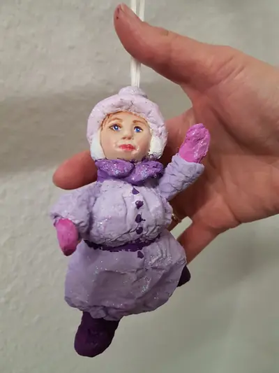 Handgefertigte Puppe im lila Wintermantel