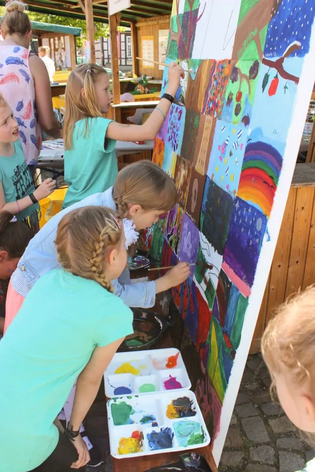 Kinder malen beim Fest der Kulturen gemeinsam an einem großen Bild