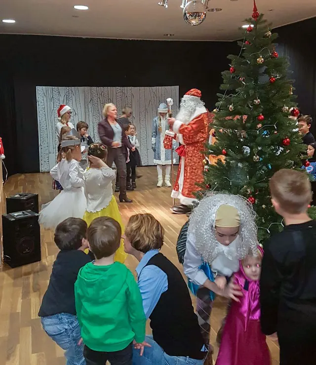 Väterchen Frost und Kinder beim Jolka-Fest am geschmückten Tannenbaum