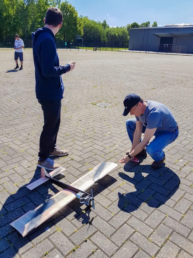 Schüler bereiten ein selbstgebautes Modellflugzeug auf dem Flugplatz zum Start vor